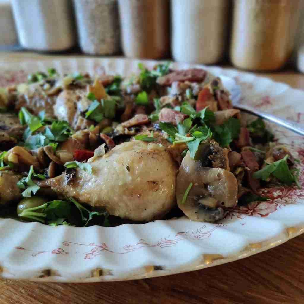 image with a dish containing pieces of chicken, mushrooms and a bit of parsley on top, you can find the recipe on the blog of Gourmandises Academie