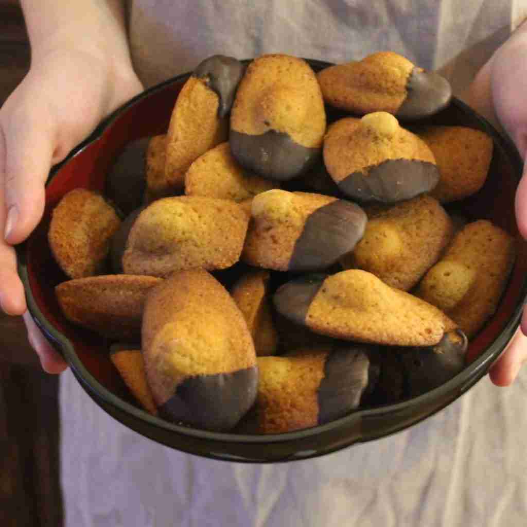 picture of a bowl containing loads of madeleines dipped in dark chocolate, you can learn how to make this recipe on the blog of cooking school gourmandises academie in Cambridge
