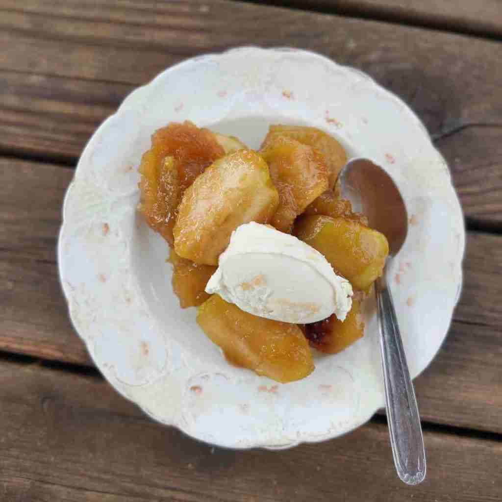 image with a plate containing pieces of caramelised apples with a dollop of cream, this recipe can be found on the blog of cookery school Gourmandises a Academie in Cambridge