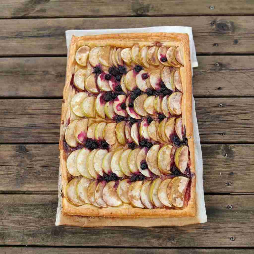 Image of an apple pie on a wooden table, the recipe can be found on the blog of cooking school Gourmandises Academie