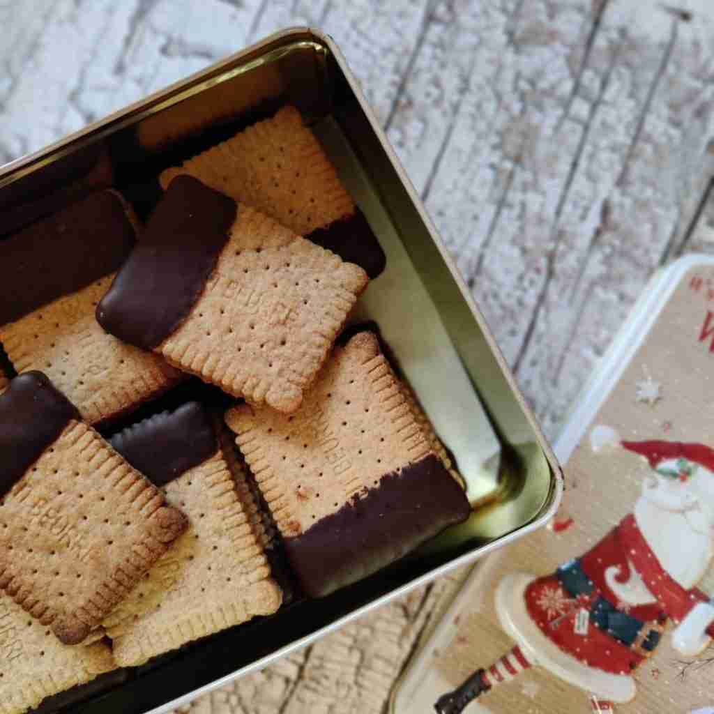 image of a box of biscuits that have been dipped in dark chocolate and the lid on the side of the box with a father christmas on it, you can learn how to make these biscuits at cookery school gourmandises academie, cambridge