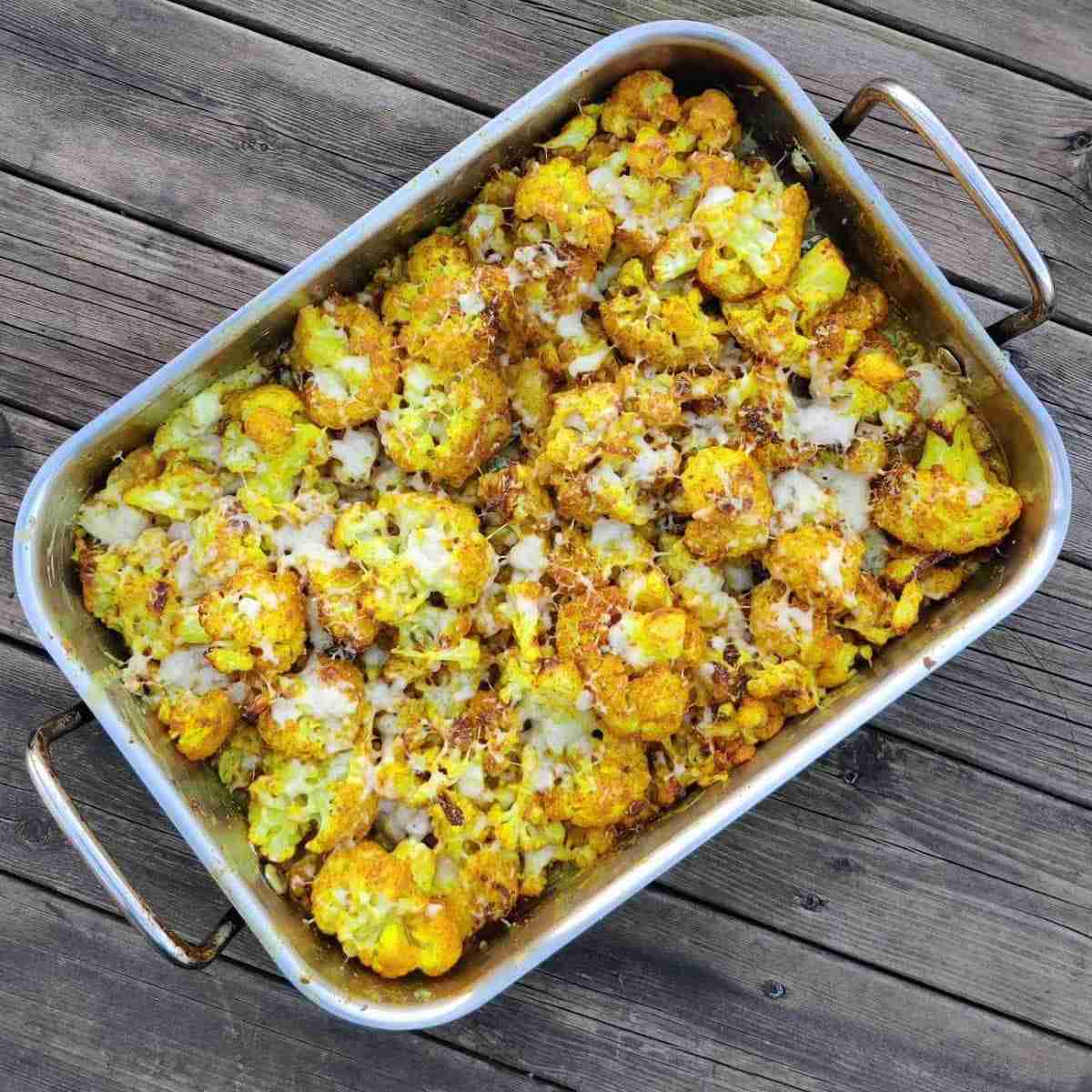 image with a baking tray filled with baked yellow cauliflower and cheese, you can find the recipe on the blog of cooking school, gourmandises academie, cottenham