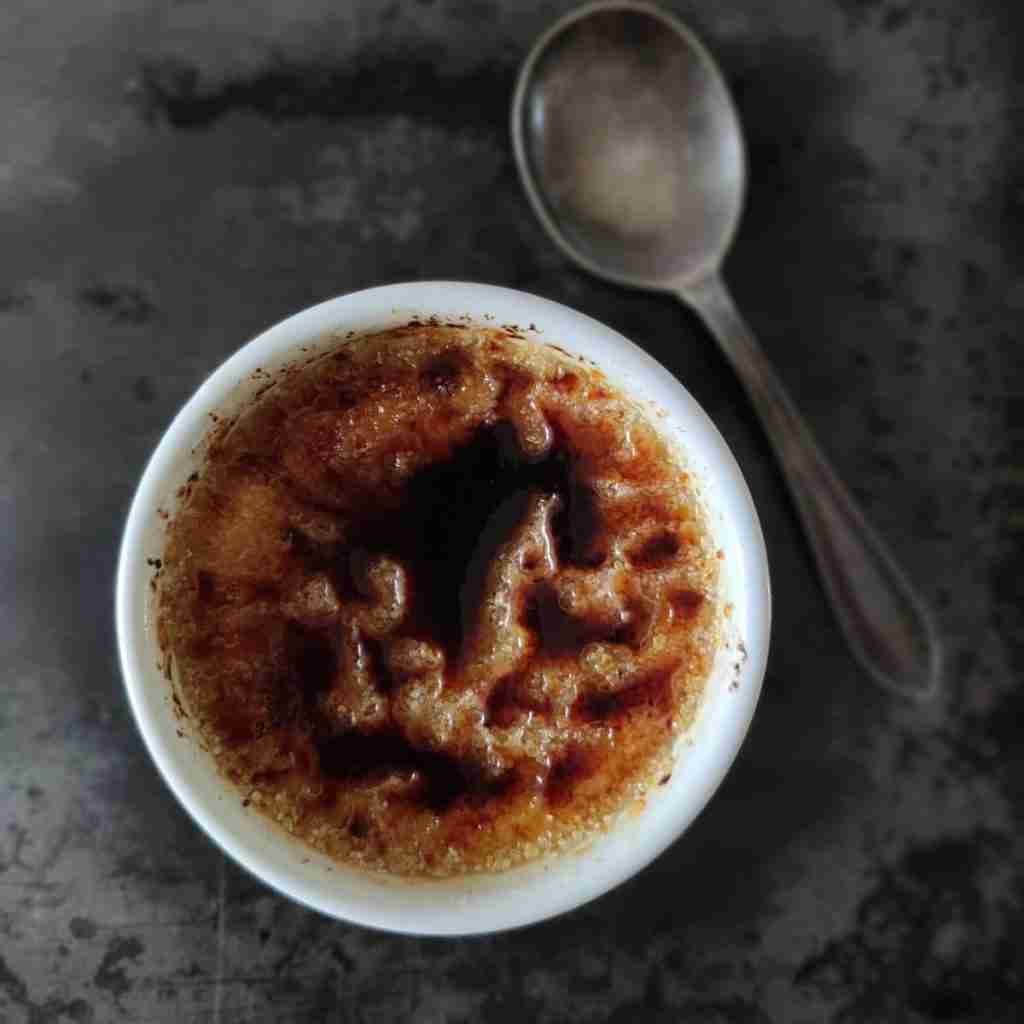 image with a dark background with a spoon and a creme brulee, you can find the recipe on the blog of cookery school gourmandises academie, cambridge