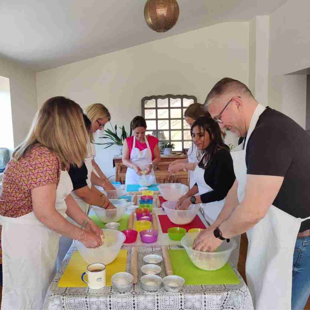 image of a group of people gathered around a table with coloured mats, making dough during a corporate team bonding activity at cookery school gourmandises academie, Cambridge