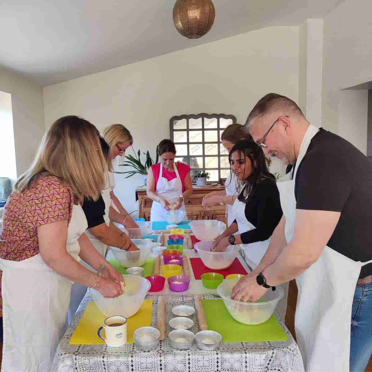 image of a group of people gathered around a table with coloured mats, making dough during a corporate team bonding activity at cookery school gourmandises academie, Cambridge