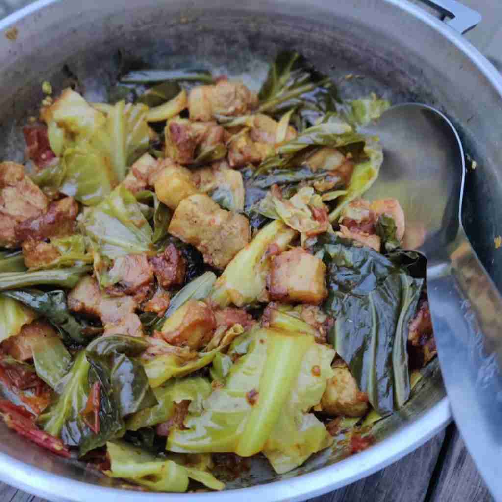 Image with a pot containing belly pork cooked with cabbage leaves, recipe can be found on the blog of cooking school Gourmandises Academie, Cambridge