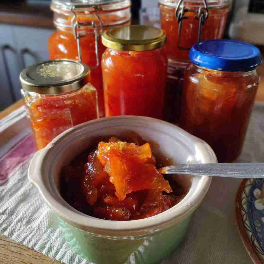 picture of a small glazed green terracota pot with orange marmalade inside and 5 jars of marmalade, recipe is available on the blog of cookery school Gourmandises Academie, Cambridge