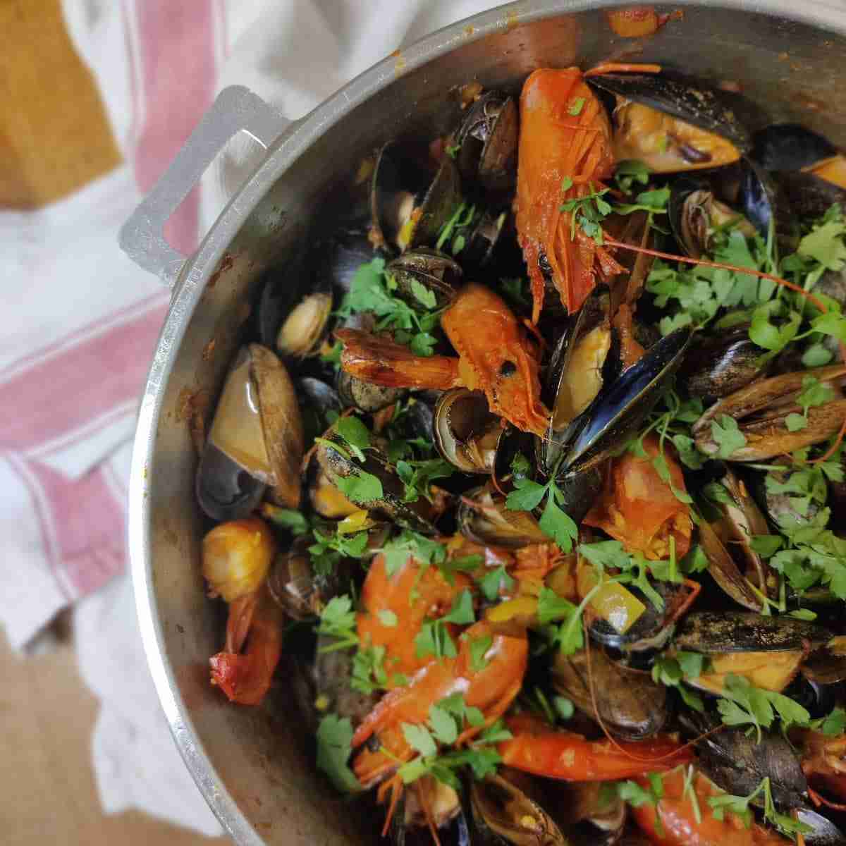 Picture of a tiger prawns and mussel cari, still in the pan, with parsley on top, the recipe is available on the blog of the cookery school Gourmandises Academie, Cambridge