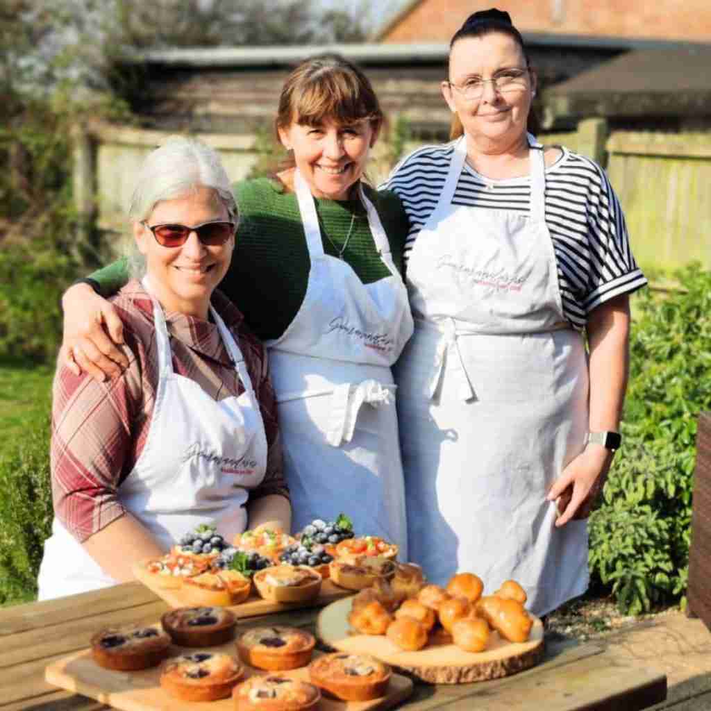 image with three ladies outside with a table showcasing a variety of tartelettes and profiteroles