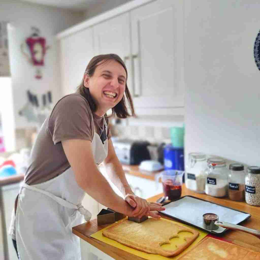image of a very happy man, cutting through a sponge with a round cutter during a patisserie class at Gourmandises Academie