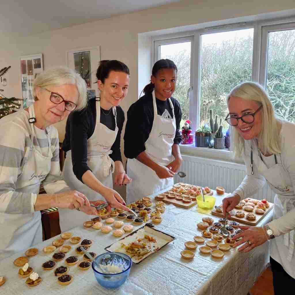 image of four ladies smiling and filling an array of mini tartelettes