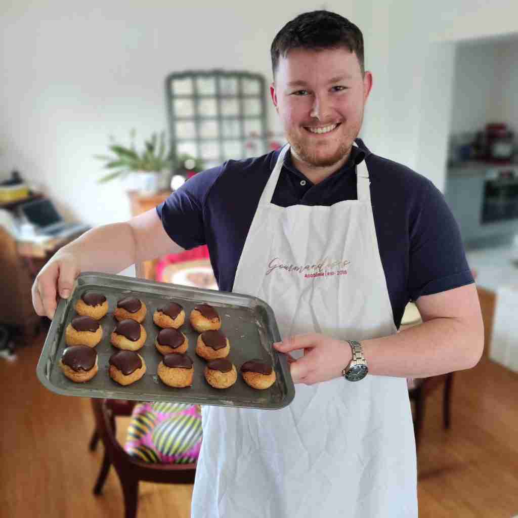 image of a happy boy holding a tray of chocolate profiteroles, you can learn how to make them at cookery school Gourmandises Academie, Cambridge