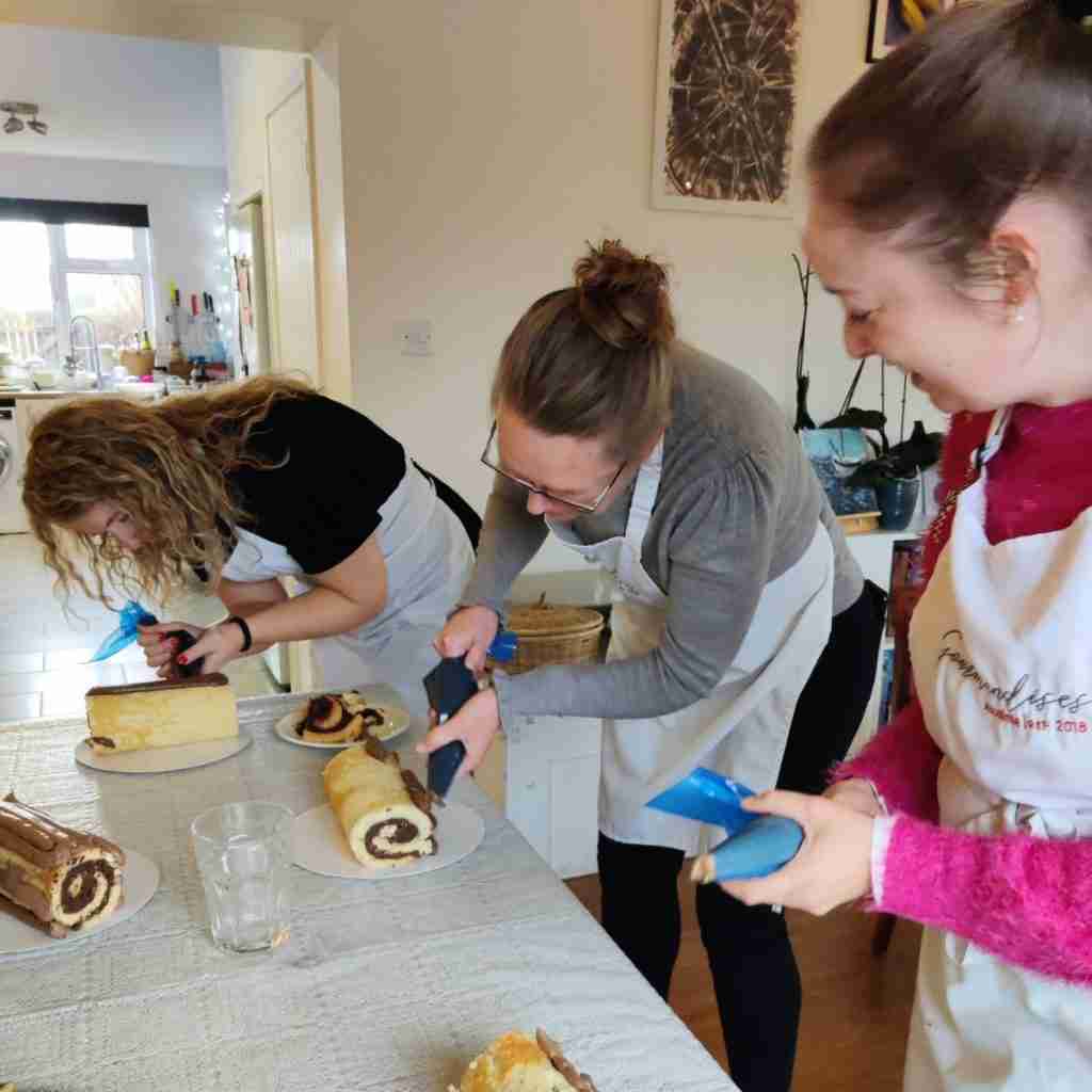 image of three ladies piping chocolate icing to their buche de noel