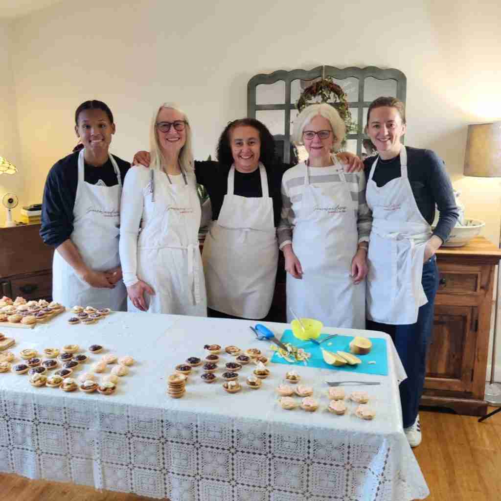 image of five ladies in front of a table filled with sweet and savoury canapes from a Christmas cookery class at Gourmandises Academie, Cambridge