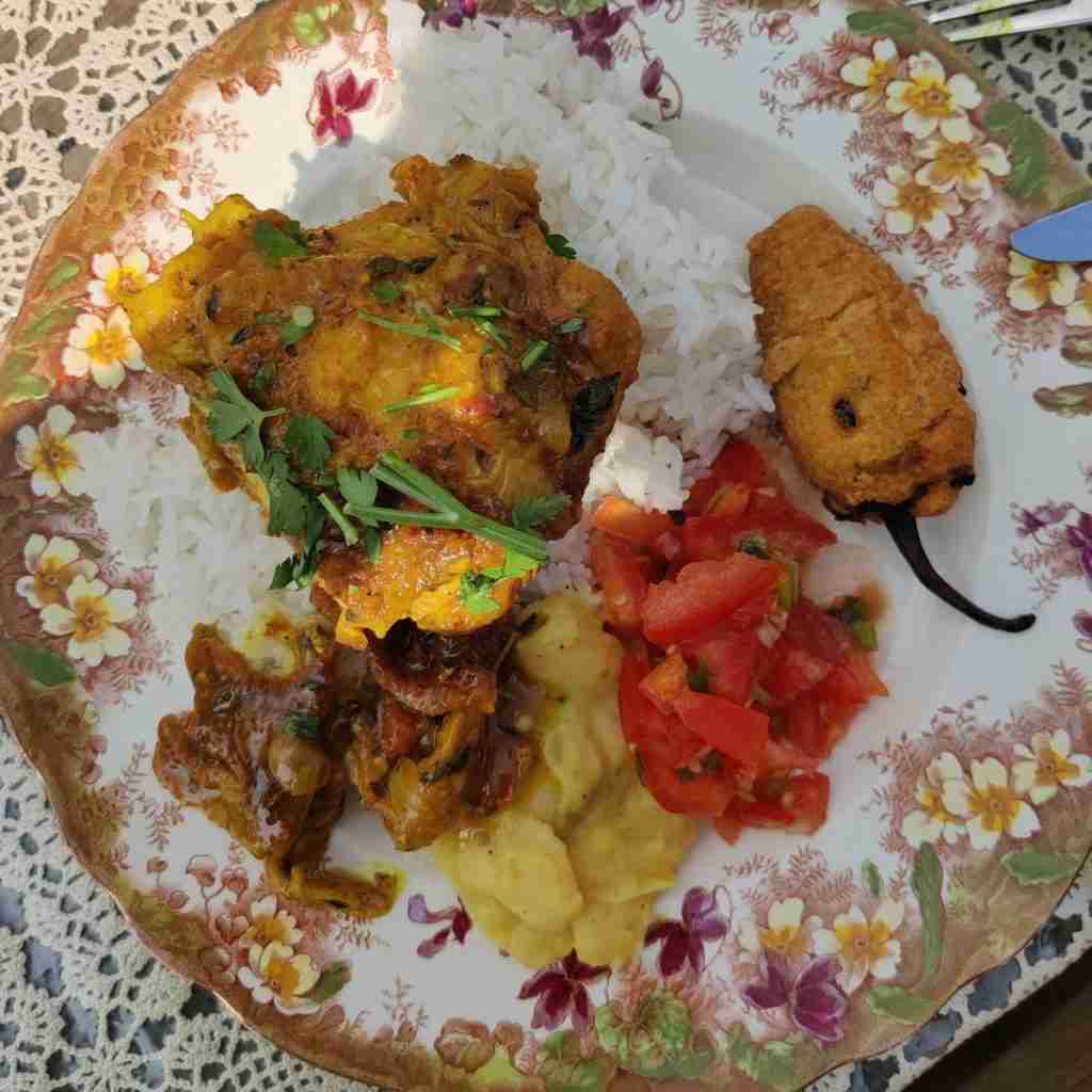 image of a plate of food filled with rice, tomato rougail, chicken thigh, and bean stew, from the cookery class on Reunion Island at cooking school gourmandises academie, cambridge