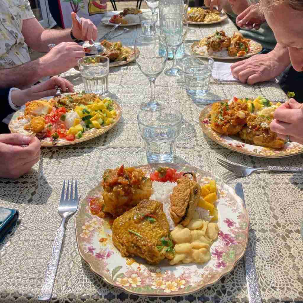 image of a table laid out outside with plates full of food, curried chicken, bean and rice