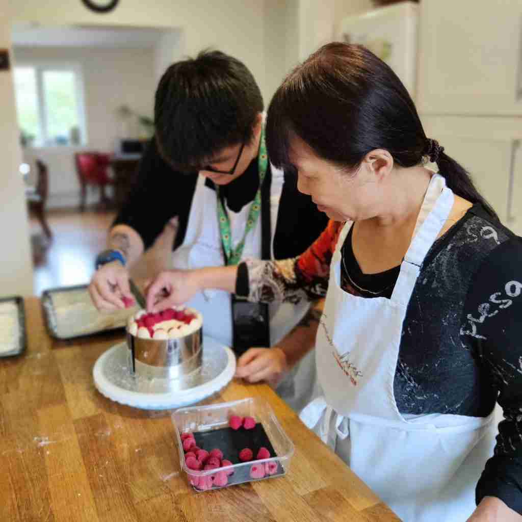 image of mother and son decorating a raspberry charlotte during a baking class at Gourmandises Academie, Cambridge