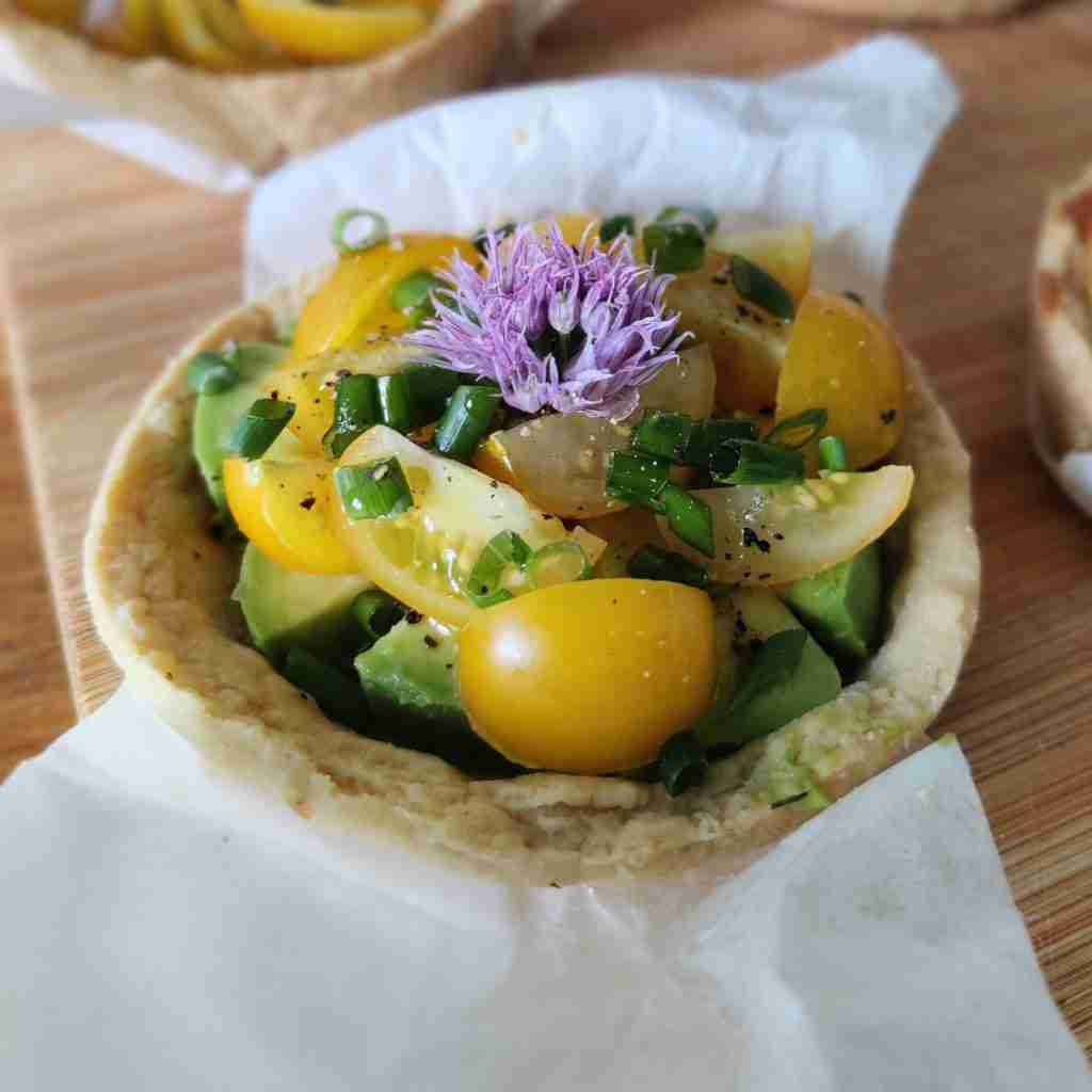 image of a tartelette filled with fresh tomatoes, cucumbers and chives flowers