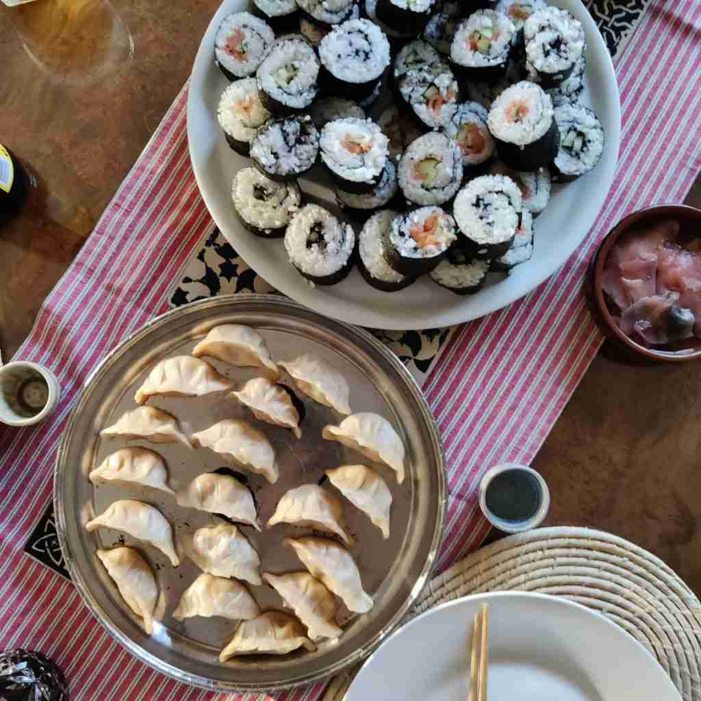 image of a table laden with Japanese Gyoza and sushi, you can learn how to make gyoza at cooking school gourmandises academie cambridge