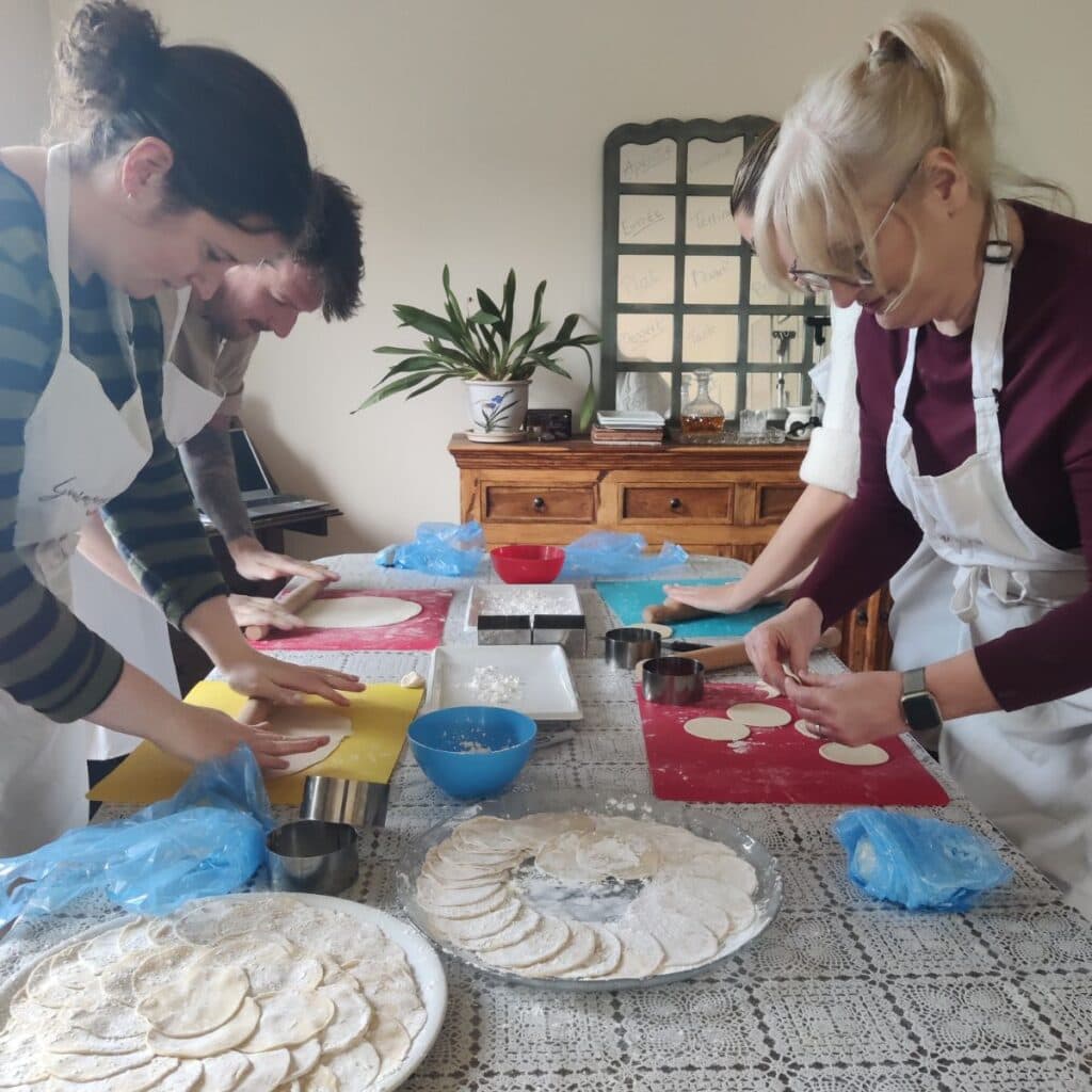 image of 4 people rolling and shaping dumpling dough during a gyoza class at cookery school Gourmandises Academie, Cambridge