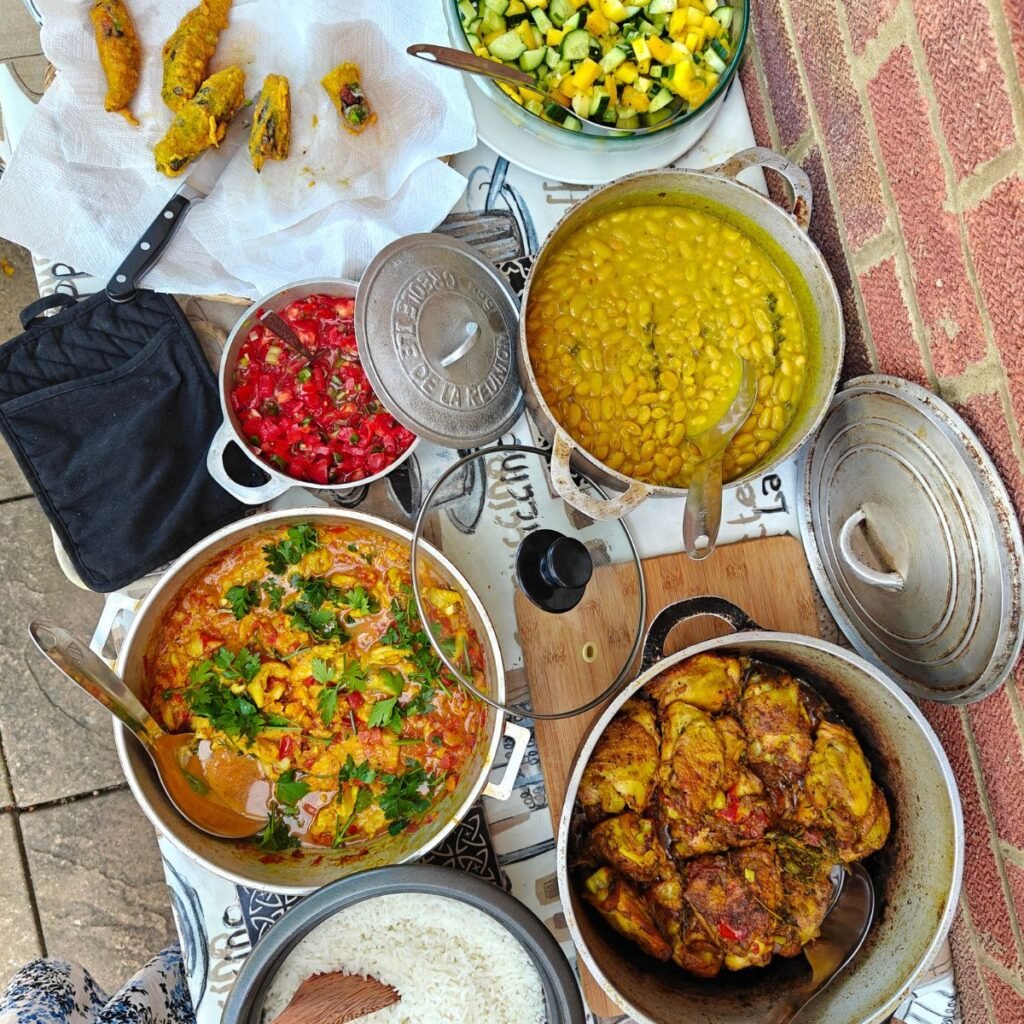 Picture of a table laden with dishes from Reunion Island, fish, chicken, bean stew, tomato rougail, exotic salad and stuffed chillies