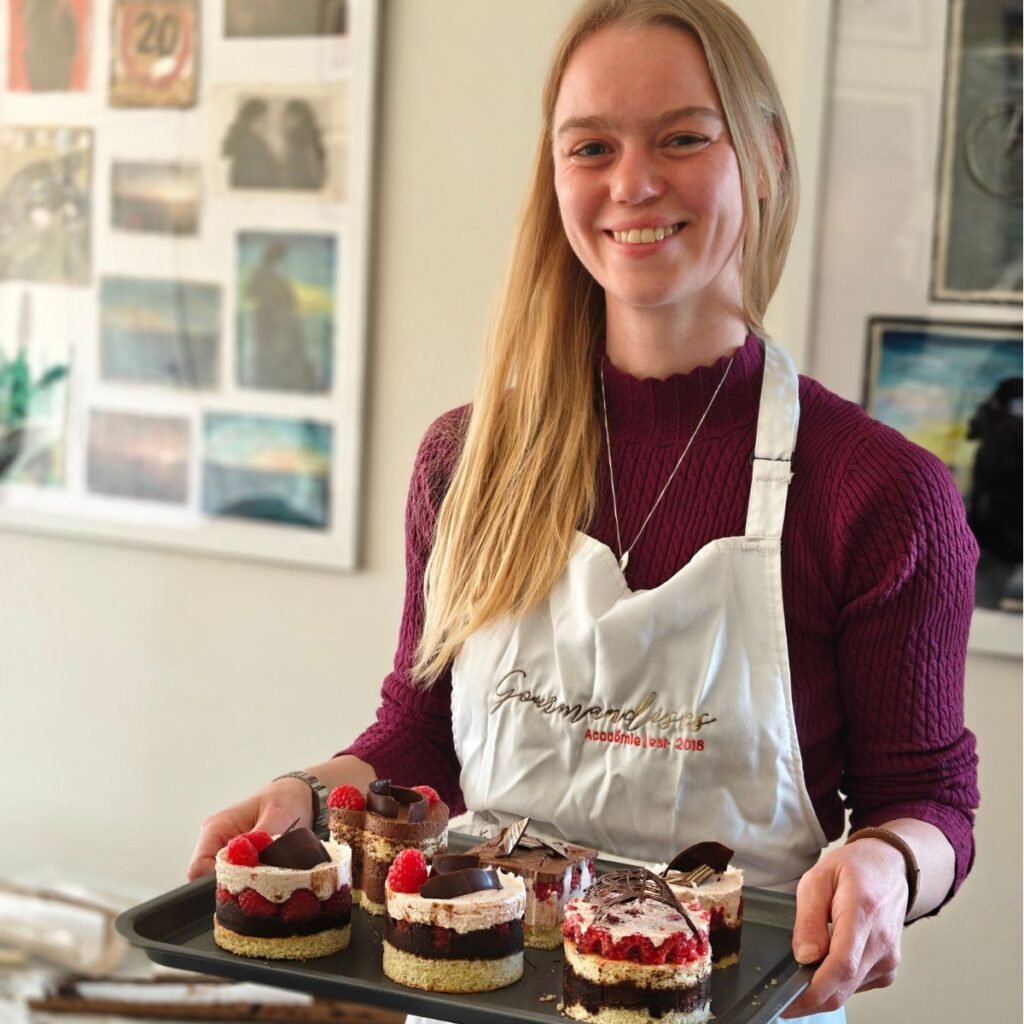 image of a girl smiling with a tray of petits gateaux she made during a patisserie class at gourmandises academie in cambridge